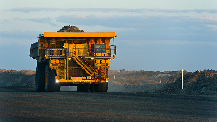 A large loaded mining truck drives through a featureless landscape.