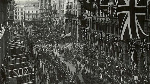 Photograph showing the Royal procession passing along Martin Place towards the Commonwealth Bank.  The foreground shows the procession turning into Pitt Street.